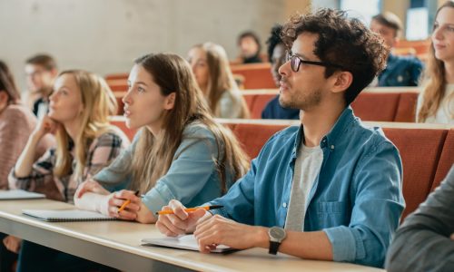 In the Classroom Multi Ethnic Students Listening to a Lecturer and Writing in Notebooks. Smart Young People Study at the College.