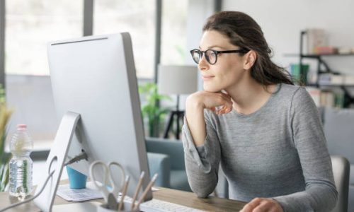 Professional woman sitting at desk and connecting with her computer, she is working from home